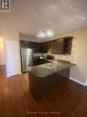 Woodstock (Woodstock - South) condo for rent - A kitchen with a stainless steel refrigerator and wooden floors.