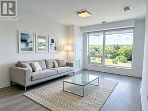 Richmond Hill (South Richvale) condo for rent - A living room with a grey couch, a glass coffee table, and a large window with a view of trees.