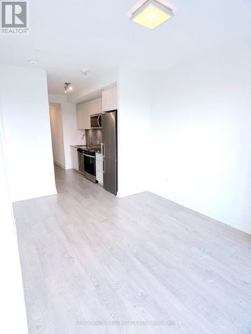 Richmond Hill (South Richvale) condo for rent - A kitchen with white cabinets and a black fridge is visible from a hallway.