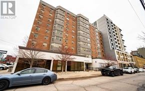 Guelph (Downtown) condo for rent - A car is parked in front of a building with a sign that says "Royal LePage Meadowtown Realty, Brokerage.".