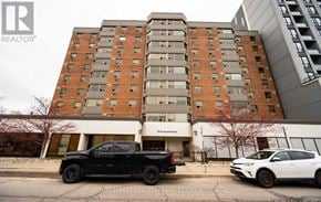 Guelph (Downtown) condo for rent - A black pickup truck is parked in front of a multi-story building.