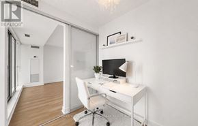 Toronto (Niagara) condo for rent - A white desk with a computer and lamp in a room with a white chair and a white wall.