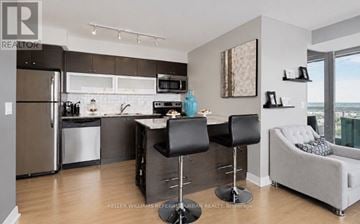 Toronto (Niagara) condo for rent - A modern kitchen with a refrigerator, microwave, and a dining table with chairs.