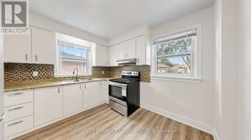 Oshawa (Donevan) apartment for rent - A kitchen with white cabinets and a black dishwasher.