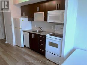 Toronto (Bendale) house for rent - A kitchen with white appliances and brown cabinets.