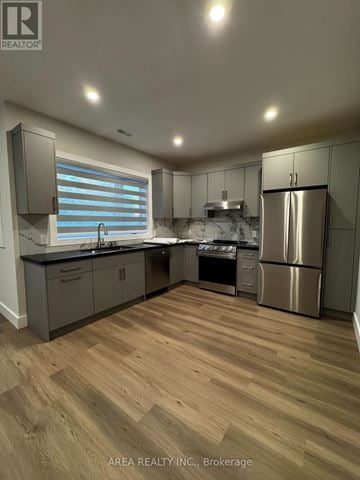 Toronto (Oakwood Village) triplex for rent - A modern kitchen with wooden flooring and stainless steel appliances.