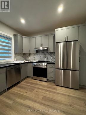 Toronto (Oakwood Village) triplex for rent - A modern kitchen with wooden floors and stainless steel appliances.