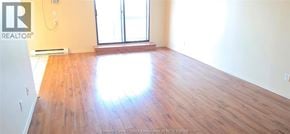 Windsor condo for rent - A room with wooden floors and a large window.