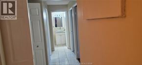 Windsor condo for rent - A hallway with a door on the left and a bathroom in the distance.