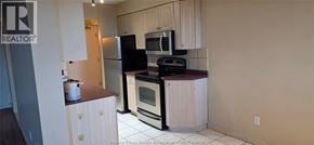 Windsor condo for rent - A kitchen with white cabinets and a black fridge.