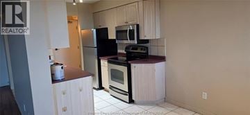 Windsor condo for rent - A kitchen with white cabinets and a black fridge.