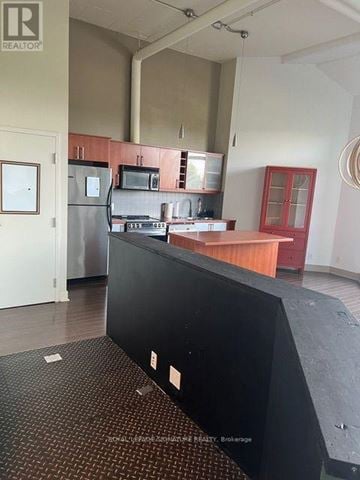 Toronto (Briar Hill-Belgravia) condo for rent - A kitchen area with a black counter and a fridge.