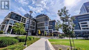 Oakville (Jm Joshua Meadows) condo for rent - A modern building complex with a clear blue sky above.