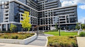 Oakville (Jm Joshua Meadows) condo for rent - A modern building with a glass facade and a tree in front.