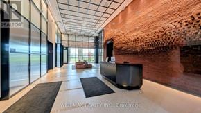 Oakville (Jm Joshua Meadows) condo for rent - A modern office lobby with a wooden wall and black furniture.