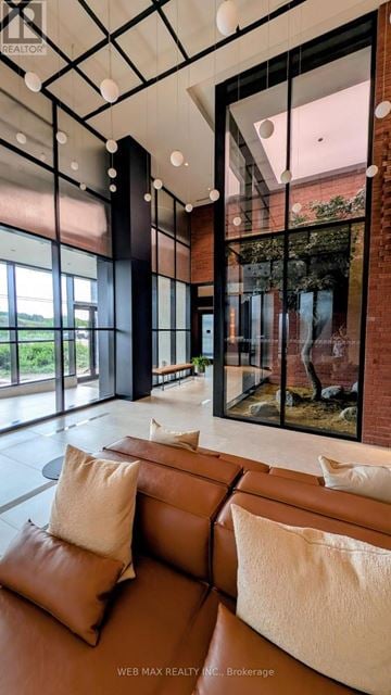 Oakville (Jm Joshua Meadows) condo for rent - A modern living room with a brown leather couch and a glass wall.