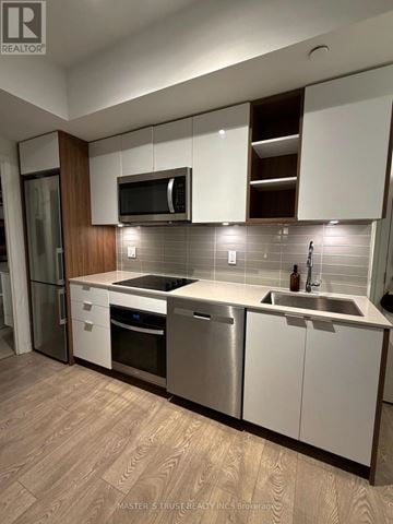 Toronto (Waterfront Communities) condo for rent - A kitchen with white cabinets and a wooden accent wall.