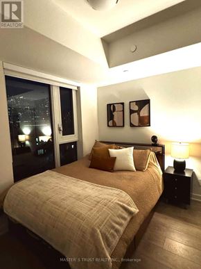 Toronto (Waterfront Communities) condo for rent - A bedroom with a bed, nightstands, and pictures on the wall.