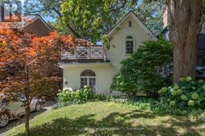 Toronto (The Beaches) apartment for rent - A yellow house with a white fence and a tree with red leaves in front of it.