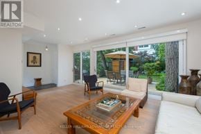 Toronto (The Beaches) apartment for rent - A living room with a white couch, a wooden coffee table, and a view of a backyard through the glass doors.