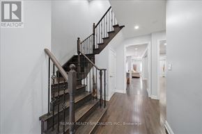 Bradford West Gwillimbury (Bradford) apartment for rent - A wooden staircase with a metal railing leads to a brightly lit hallway.
