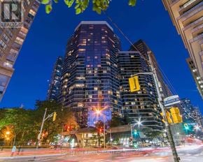 Toronto (Bay Street Corridor) condo for rent - A city street at night with a tall building in the background.