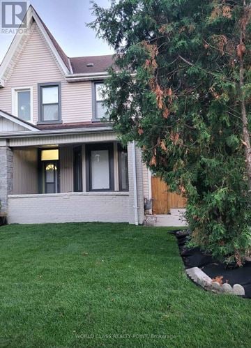 Toronto (Junction Area) duplex for rent - A house with a large front yard and a tree in the front.