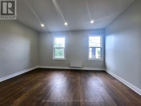 Toronto (Junction Area) duplex for rent - A room with wooden floors and two windows.