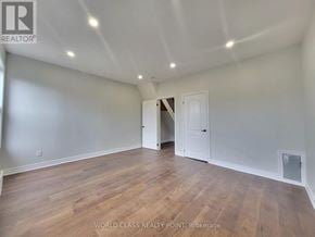 Toronto (Junction Area) duplex for rent - A spacious room with wooden flooring and white walls, with a doorway leading to another room.