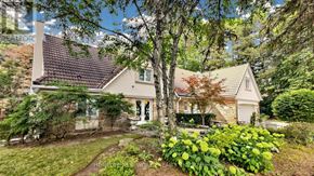 Markham (Bayview Glen) apartment for rent - A house with a white exterior and a brown roof is surrounded by greenery.