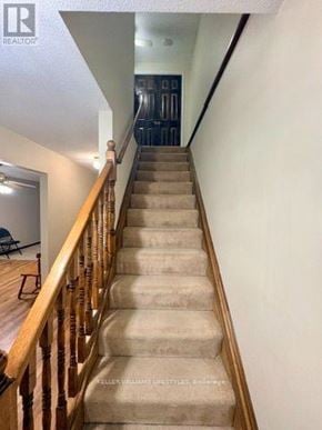 London East (East H) townhouse for rent - A staircase with a wooden railing and beige carpeted steps.