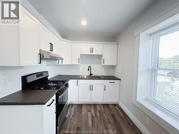 Chatham apartment for rent - A kitchen with white cabinets and a black stove top oven.