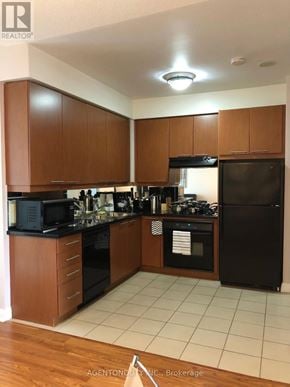 Toronto (Bay Street Corridor) condo for rent - A kitchen with wooden cabinets and black appliances.
