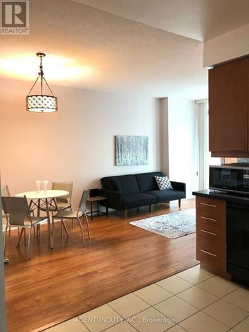 Toronto (Bay Street Corridor) condo for rent - A living room with a black couch and a dining table.