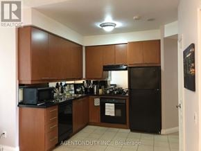 Toronto (Bay Street Corridor) condo for rent - A kitchen with brown cabinets and black appliances.