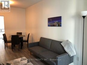 Toronto (Bay Street Corridor) condo for rent - A living room with a grey couch, a dining table with chairs, and a painting on the wall.