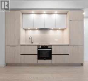 Toronto (Waterfront Communities) condo for rent - A modern kitchen with wooden cabinets and stainless steel appliances.