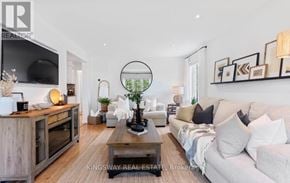 Oshawa (Centennial) apartment for rent - A modern living room with a white sofa, a wooden coffee table, and a TV on the wall.