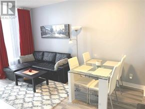 Vaughan (Beverley Glen) condo for rent - A living room with a black couch, a glass table, and a painting on the wall.