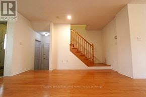 Mississauga (Lisgar) apartment for rent - A spacious room with wooden floors and a staircase.