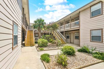 Slidell apartment for rent - A sunny day at a residential complex with a well-maintained garden in the foreground.