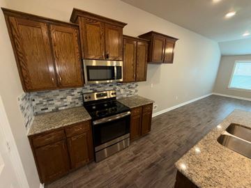 Temple townhouse for rent - A kitchen with wooden cabinets and granite countertops.