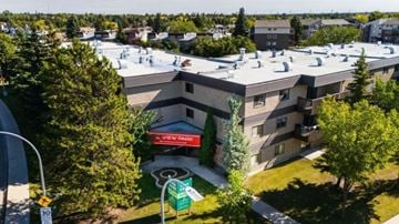 Edmonton apartment for rent - A building with a red awning and a sign that says "New Bay" is surrounded by trees.