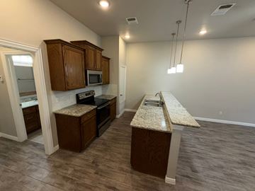 Temple townhouse for rent - A kitchen with brown cabinets and a granite countertop.