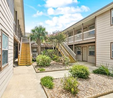 Slidell apartment for rent - A sunny day at a residential complex with a well-maintained garden in the foreground.