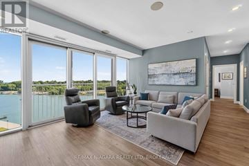 St. Catharines (Port Dalhousie) condo for rent - A living room with a couch, chairs, and a coffee table with a view of the water outside.