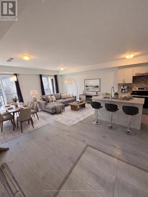 Barrie townhouse for rent - A modern living room with a kitchen area in the background.