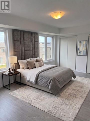 Barrie townhouse for rent - A bedroom with a large bed and a window with curtains.