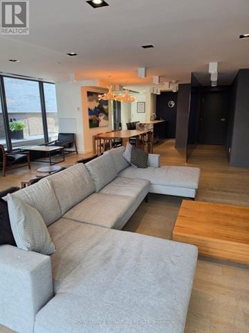 Toronto (Waterfront Communities) condo for rent - A living room with a large grey sofa and a wooden floor.