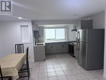 Mississauga (Central Erin Mills) apartment for rent - A kitchen with a table and chairs in the foreground and a refrigerator, sink, and cabinets in the background.